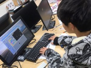 シューティングゲームをプログラミングしている中学生の男の子