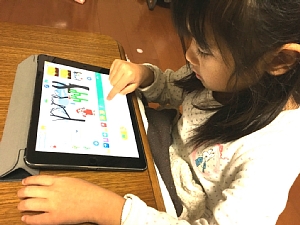 スクラッチ・ジュニアを使ってタブレットでプログラミングをしている幼稚園の女の子
