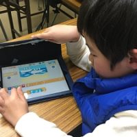 iPadで、Scratch Jrを使って、プログラミングをしている男の子