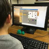 Scratchでゲームのプログラミングをしている小学生の男の子