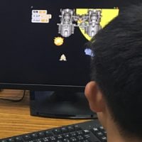 Scratchでシューティングゲームをプログラミングしている小学生の男の子